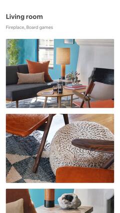 A sunny living room with modern furniture, the mahogany detail of a chair’s armrest, and a geode rock on a wooden side-table.
