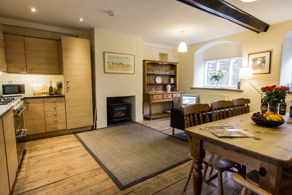 Kitchen with log effect gas fire, large farmhouse table, and 4 oven dual fuel cooker.