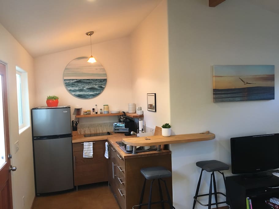 Kitchen with fridge, cooktop, sink, coffeemaker, microwave, tea pot, pots, pans, etc.