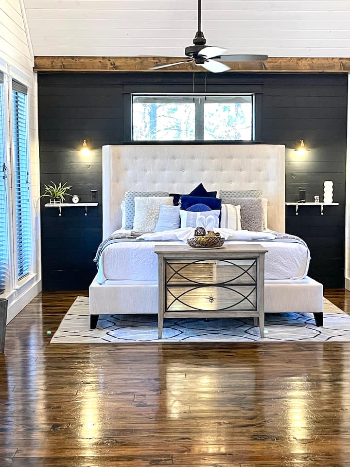 仔细看着一张加大双人床，靠着深色的缝隙墙。配备内置灯光、架子和插头，为设备充电。