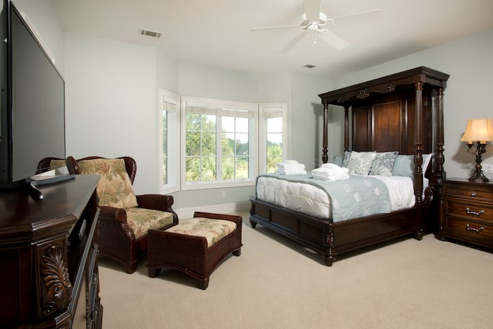 Брачна спална соба со поглед на терен за голф и пристап до балкон