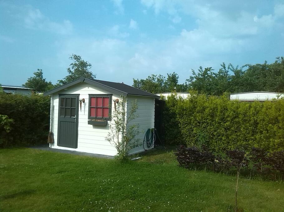 Ruime zonnige tuin met blokhut, gratis gebruik van 2 fietsen, windscherm, parasol, Barbecue, droogmolen en lichtgewicht campingstoelen.
