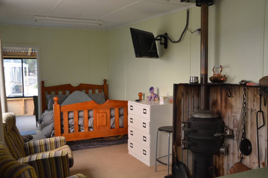 Open plan studio with Queen bed, TV, pot belly fire, kitchenette, comfy chairs by the fire.