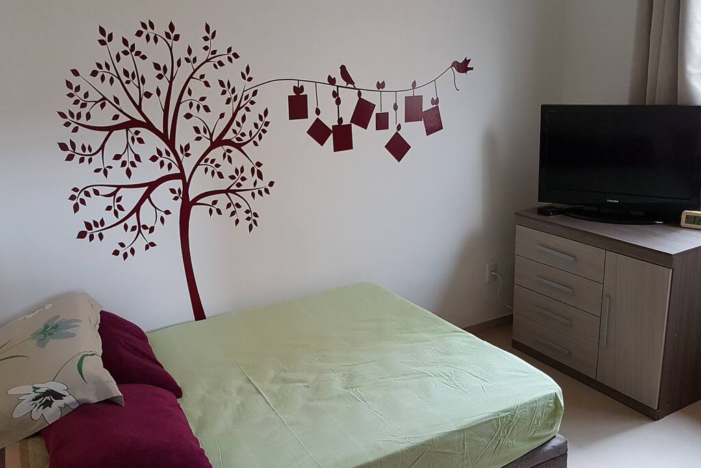 Detalhe do quarto, da cômoda e TV.