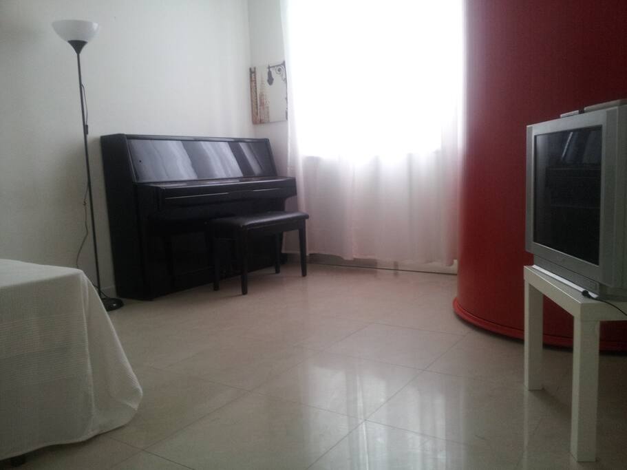 Camera da letto con pianoforte, armadio tondo rosso e TV