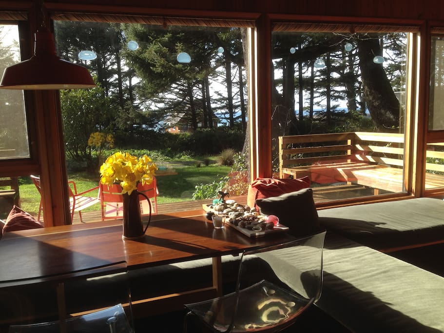Dining/Living Area facing west towards the ocean - cabin is surrounded by Sitka trees and the ocean is visible thru the trees.
