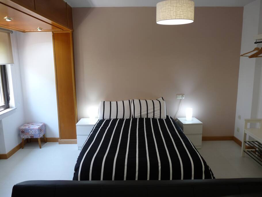 Cama doble con edredón y almohadas viscoelásticas y dos mesillas de noche con dos cajones cada una y lámparas de mesa.