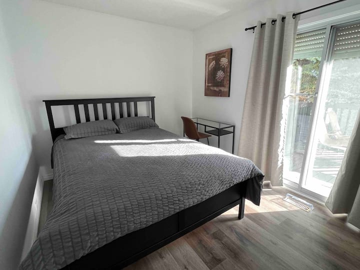 Tercer dormitorio con cama tamaño queen y escritorio y silla en la parte superior de vidrio. Mucho sol en esta habitación con puertas de techo a piso. 