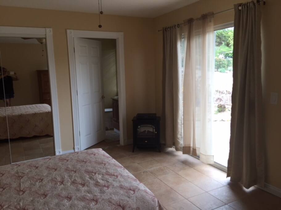 View from the door that connects the room to the rest of the house with closet on the left, bathroom door middle and sliding glass door on the right