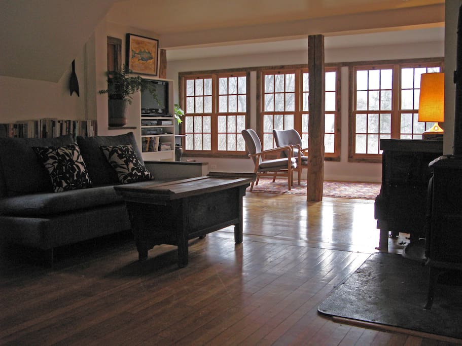 A full wall of windows in the living room overlooks a lush landscape and offers a glimpse of our private pond