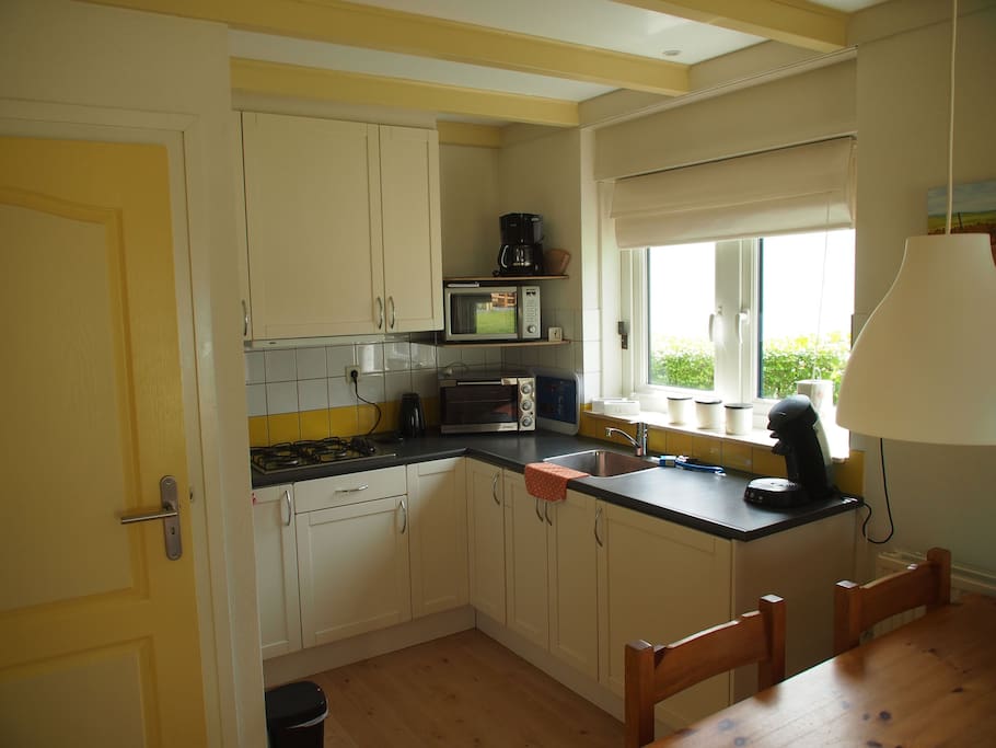 keuken met gasfornuis, koelkast, oven en magnetron