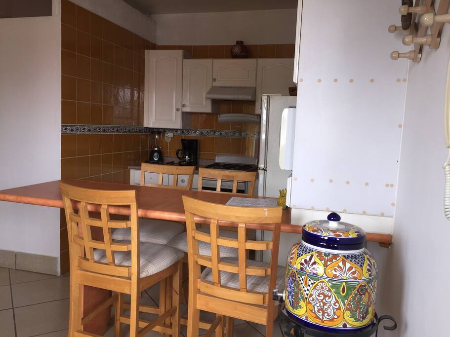 Barra comedor, cocineta, estufa, microondas, refrigerador y fregador.