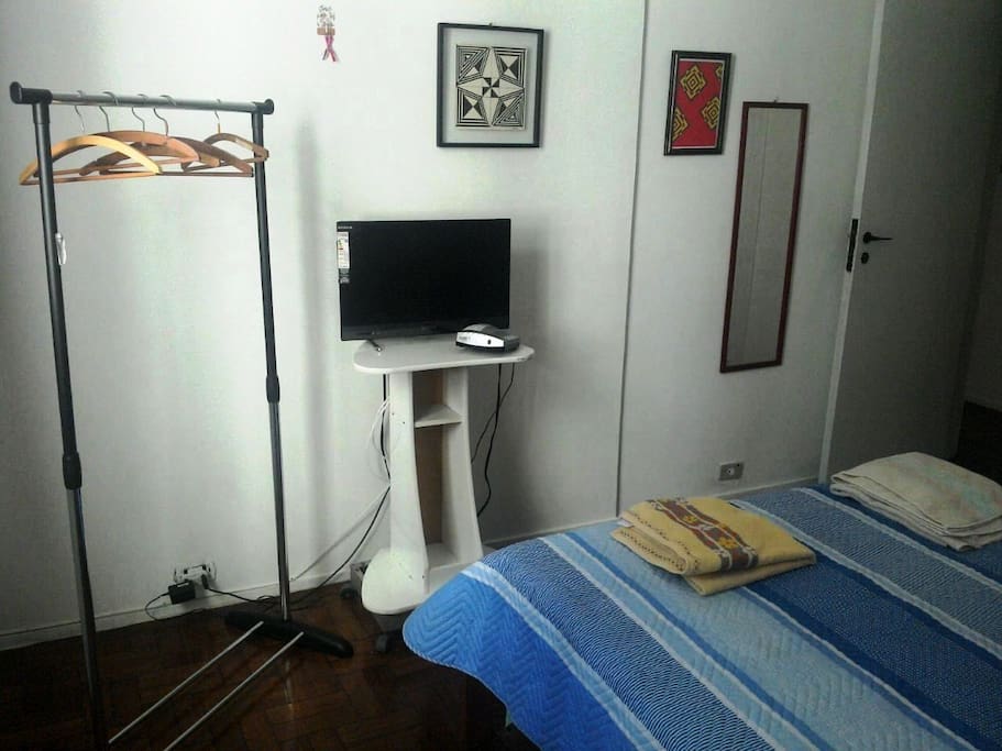 Quarto de Casal com espelho, um armário , uma arara e uma tv a cabo.