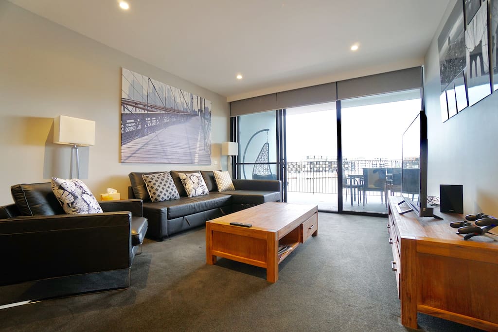 The living room with complete uninterrupted views of the Kingston Harbor and boardwalk, 55 inch TV with PS4 and Netflix, fold out bed, board games and reading material!