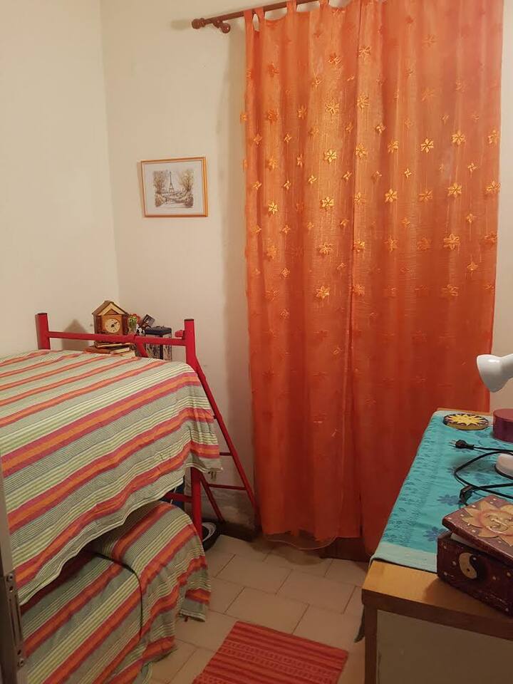 אחד משני חדרי שינה עם מיטת קומותיים ודלת חלון בגינה הקדמית