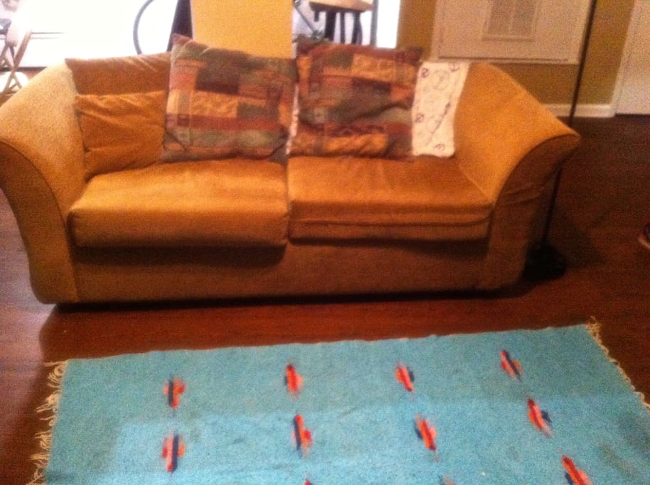Cushioned couch with all the pillows needed and peace sign covered blankie