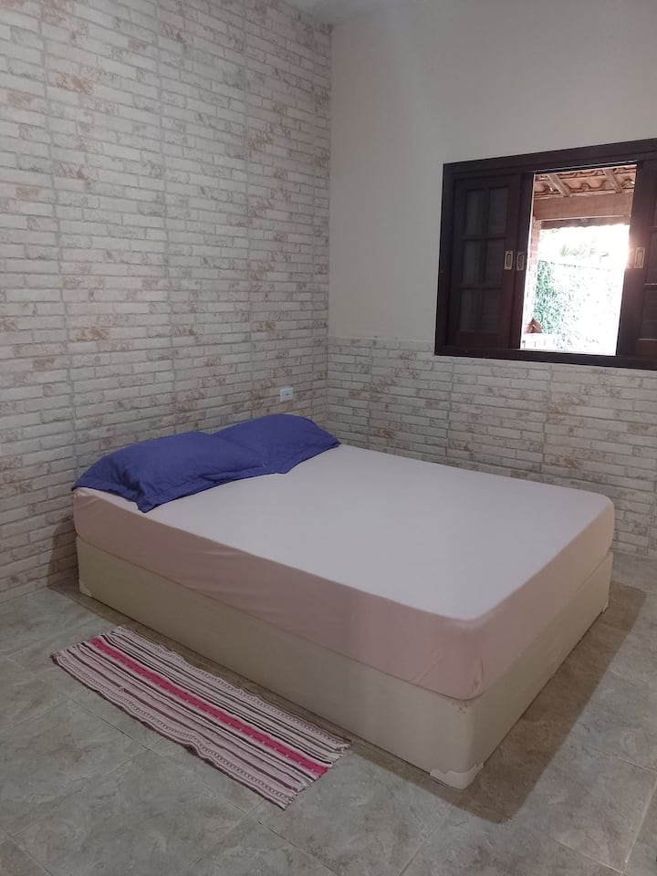 Spálňa (1) s manželskou posteľou, ventilátorom podstavca, zásuvkou a výhľadom na dvor.