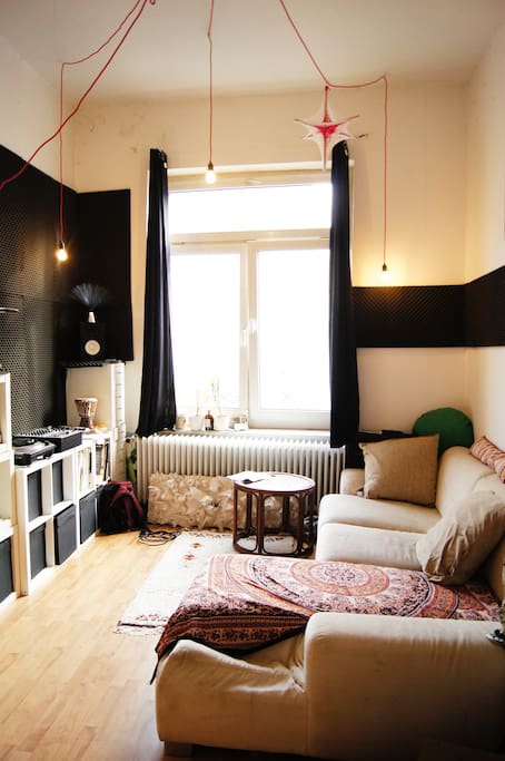 Blick Richtung Straße, die großen hellen das Zimmer mit Licht flutenden Fenster, die große Couch und das Dj-Equipment