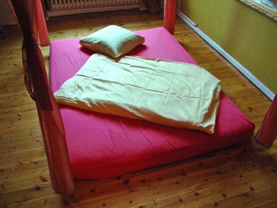 Futonbett, 140 x 200 cm unter einem Betthimmel, heimelig und wohlig.