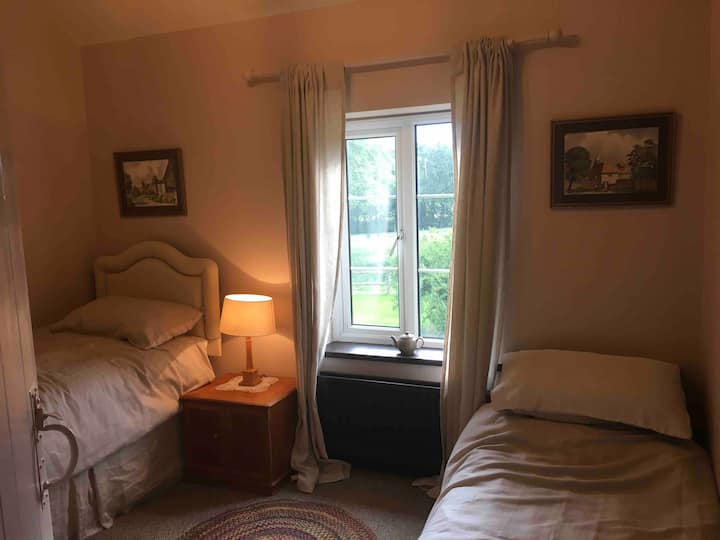 花园卧室配有两张单人床，可欣赏花园和周边田野的美景