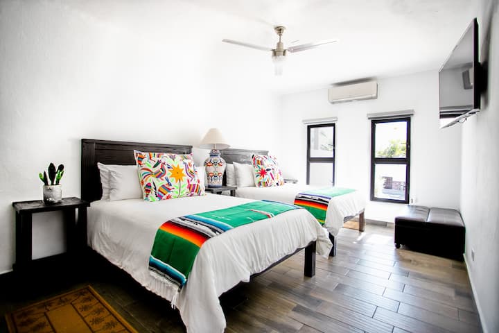 חדר שינה בקומה הראשית עם שתי מיטות זוגיות וקפל יחיד אחד