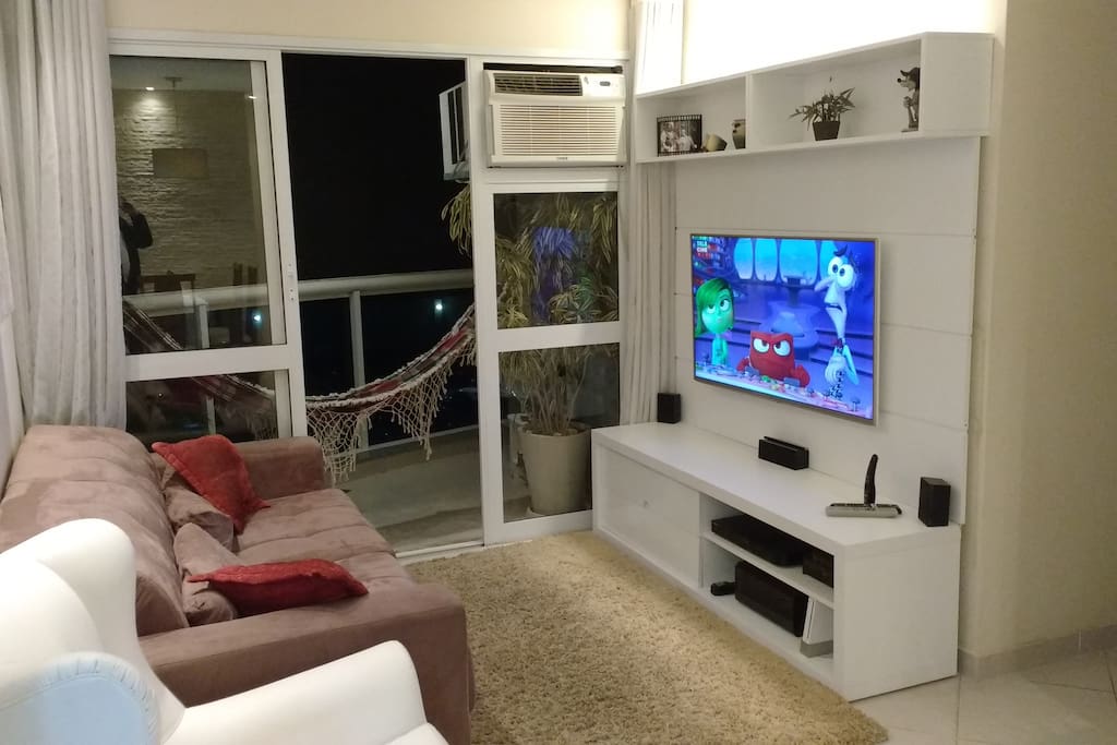Sala aconchegante, em dois ambientes, c/ ar condicionado, sofá retrátil, poltrona balanço, SmarTV 49`, TV a cabo e Internet Wi-Fi. ---- Living/Dinner Room w/ air conditioner, retractable couch, swing armchair, cable TV and Wi-Fi Internet.