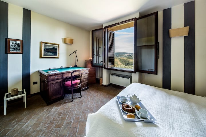 Dormitorio principal con vistas directas a San Gimignano y amplio vestidor.