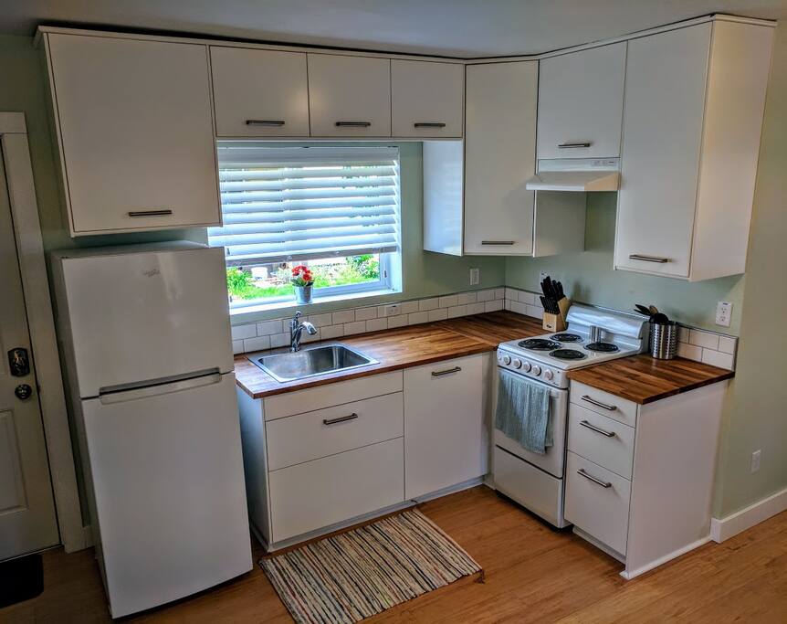 Kitchen with refrigerator and stove. Stocked with basic kitchen essentials.