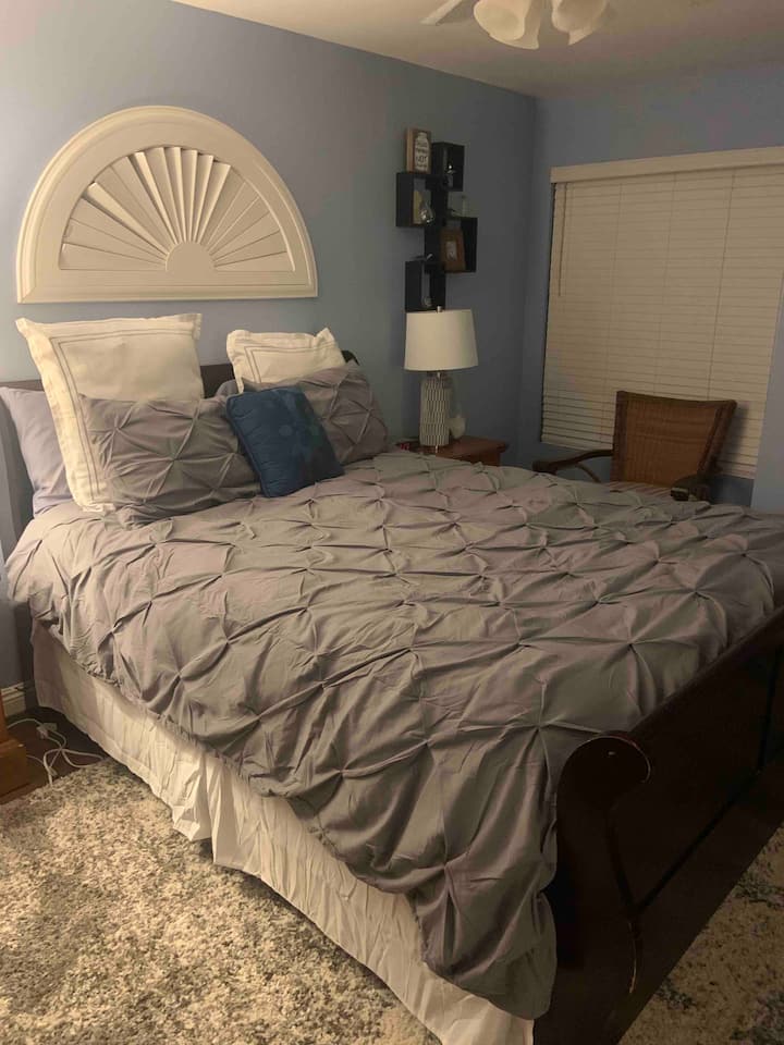 Dormitorio de invitados recientemente remodelado con azulejos nuevos y alfombra con una cama tamaño queen.