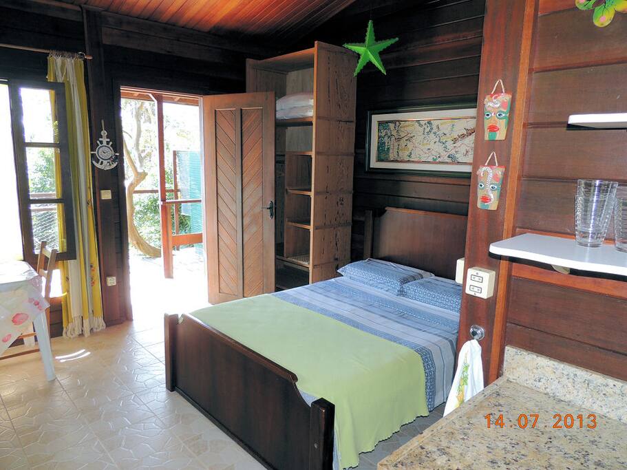 Cama de casal, janela e porta de acesso à varanda