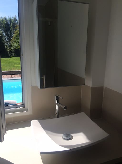 La salle de bain possède une fenêtre donnant sur la piscine et le jardin