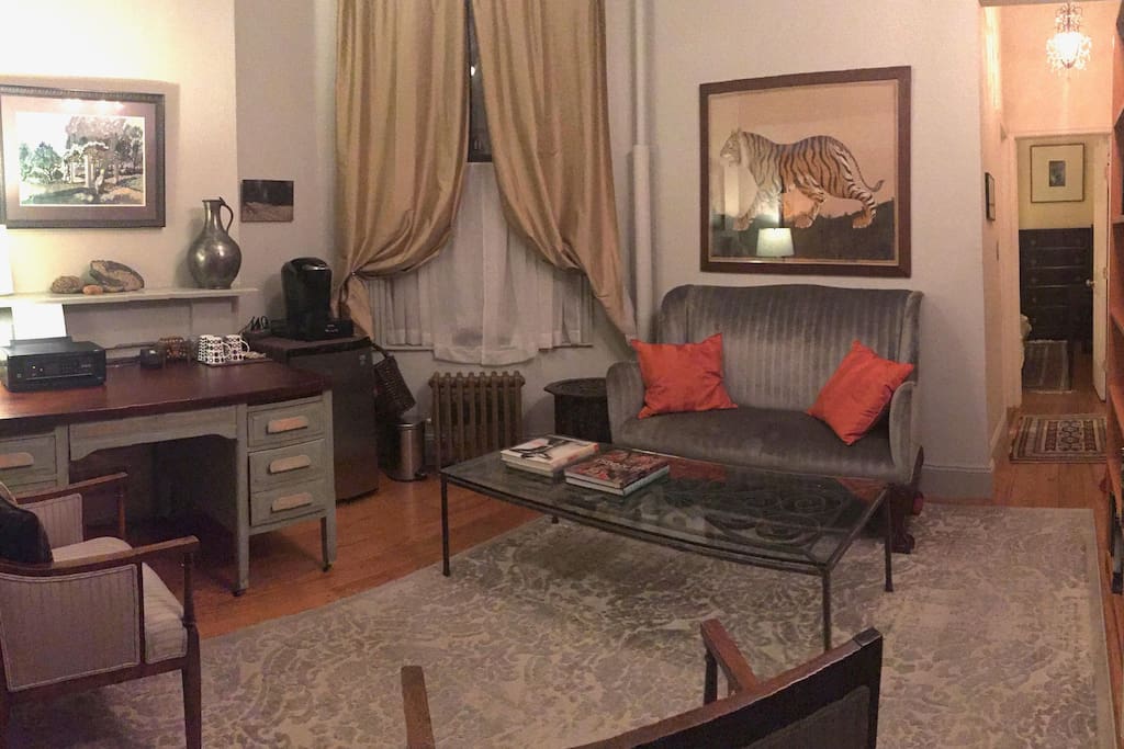 Sitting room with desk, small fridge, Keurig coffee maker, tea kettle, iron and ironing board. Art on the walls and an extensive library.