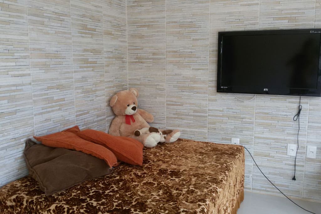 Cama do cômodo principal com televisão.