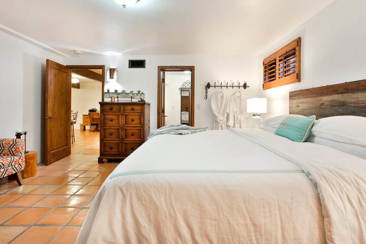 غرفة نوم بسرير بمقاس كينج وتلفزيون بشاشة مسطحة كبيرة تطل على منطقة المعيشة