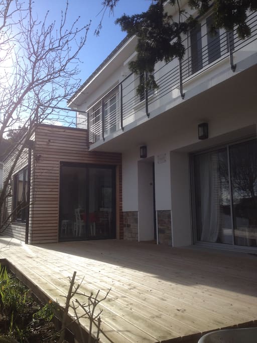 Le séjour, la salle à manger et la cuisine donnent sur une grande terrasse en bois