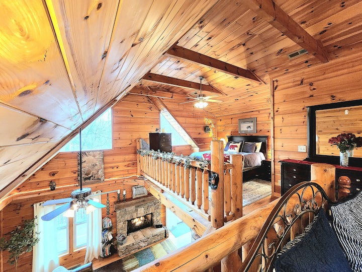 Kuangalia kwenye roshani hadi kwenye madirisha makubwa 2 ya pembetatu. Unaweza kuona eneo kuu la kitanda na ghorofa ya chini.