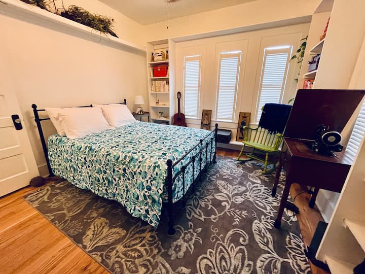 Queen bedroom with walk in closet and three large windows for Florida Sunshine. Room is sprinkled with historical sewing machines, typewriter and classic books.