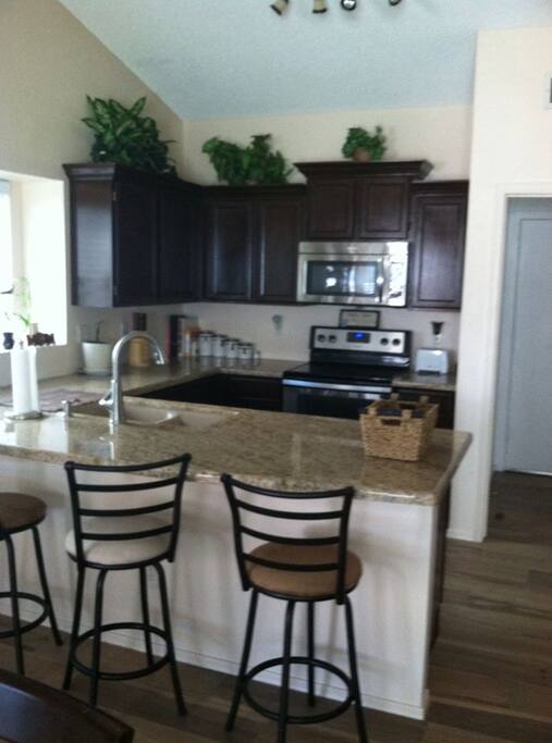 Kitchen with large, granite countertop, new appliances.