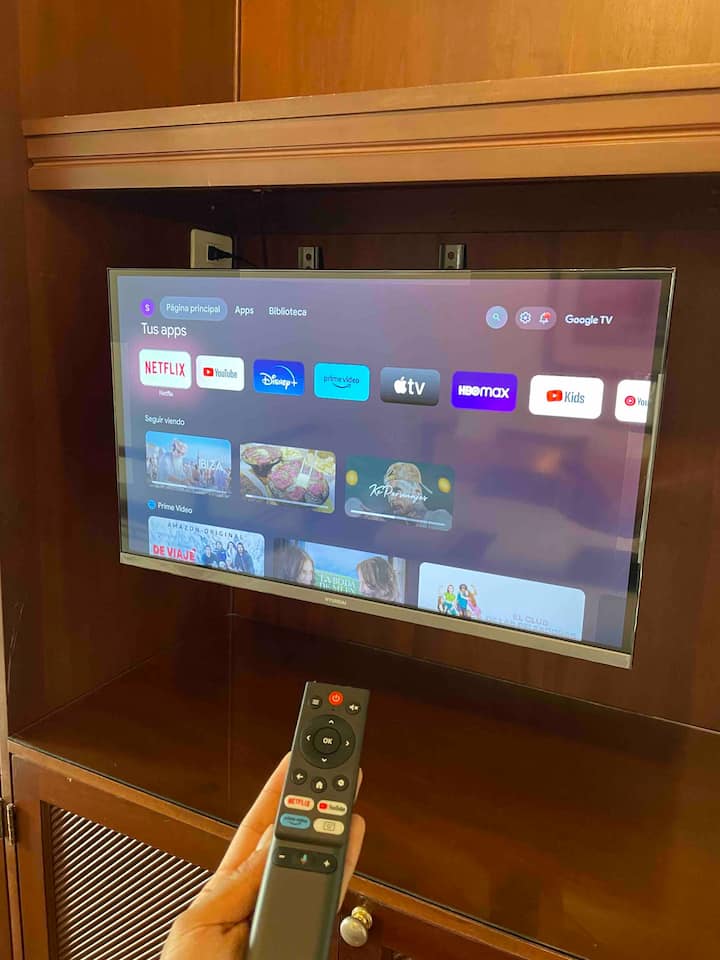 Excelente velocidad de 200 mb. Smart TV 2023 con fácil control remoto frente a la cama tamaño queen.