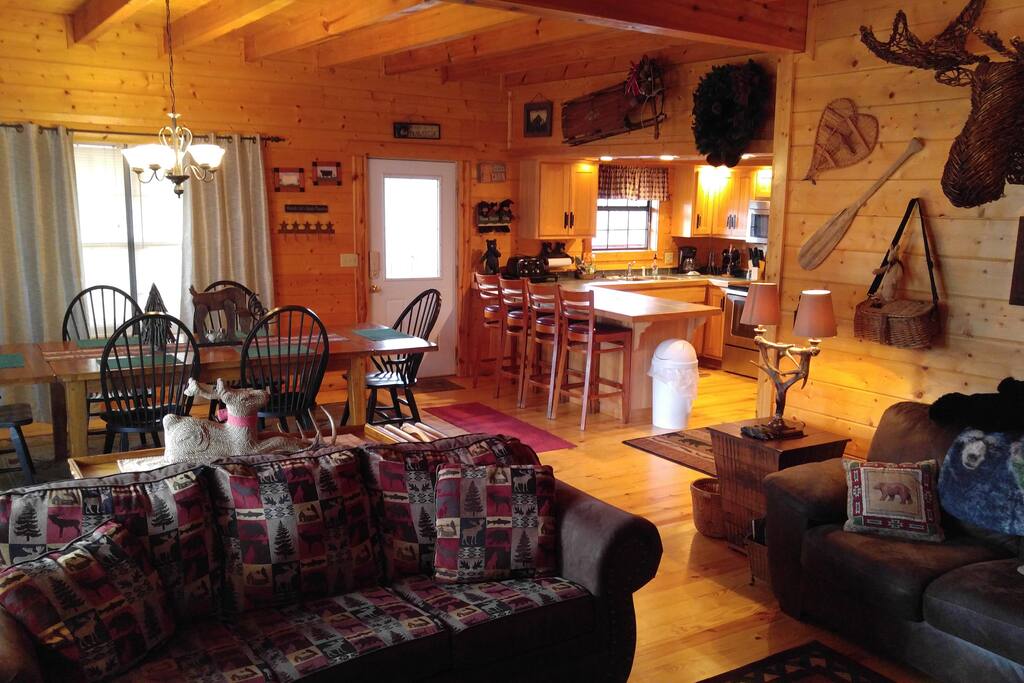 Large open area with kitchen plus island with 4 stools, plus extra long dining table for 8 plus living area with sofa, love seat, chairs, wall to floor stone fireplace, tv