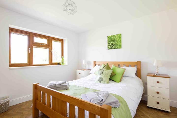 Chumba cha kijani,chumba cha kulala 1, kitanda cha mfalme cha ghorofa ya chini na makabati ya kando ya kitanda, WARDROBE, na kifua cha droo.