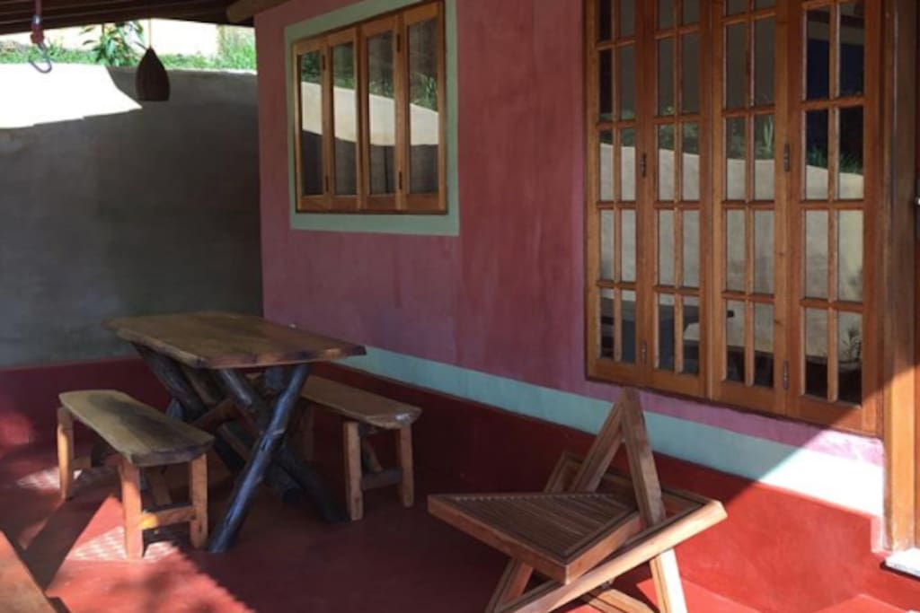 Varanda externa com mesa de jantar, cadeira e rede.
