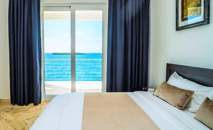 Dormitorio con cama doble, baño privado con ducha, aire acondicionado, ventilador de techo, seguro e impresionantes vistas al mar.
