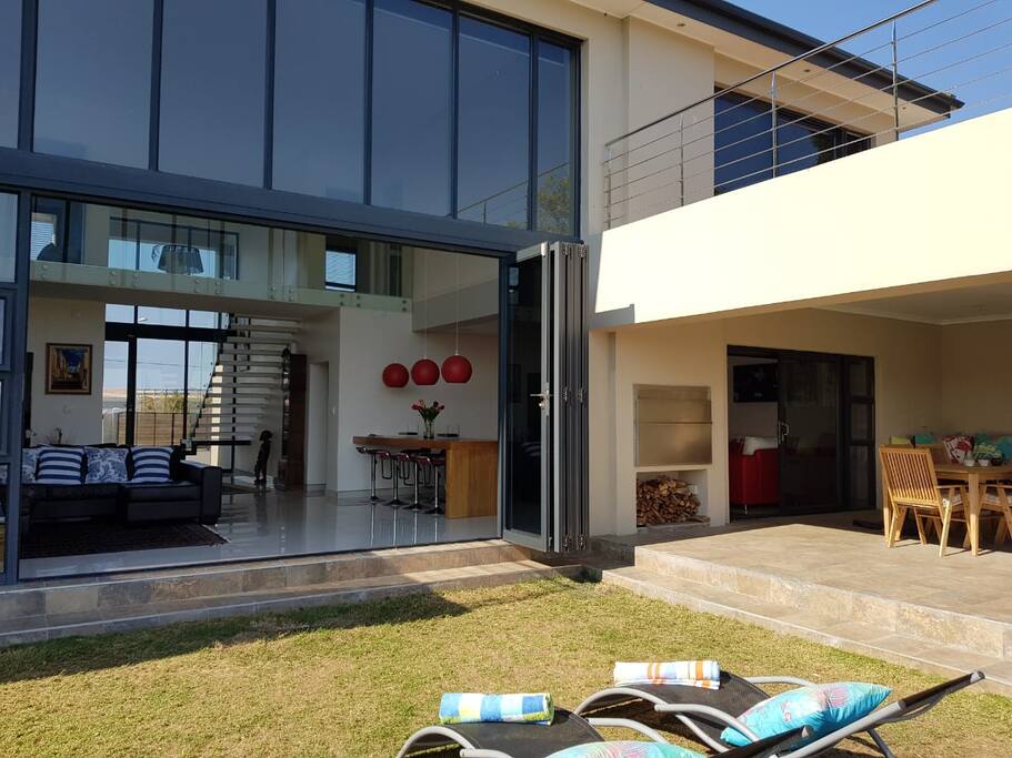 River view of house with stack doors opening out to a swimming pool, entertainment area with outdoor braai and pizza oven