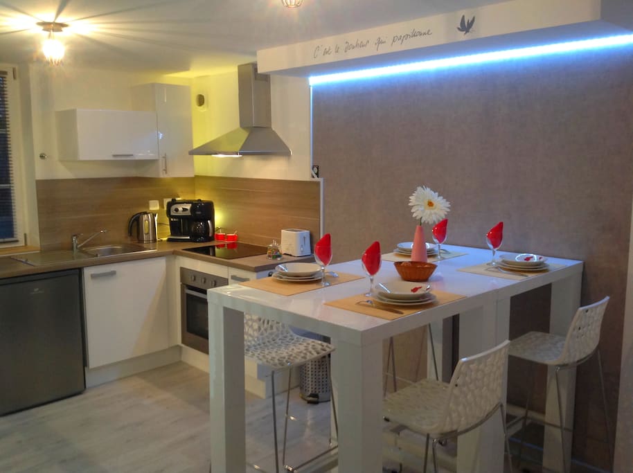 Cuisine vue depuis la porte d'entrée avec 2 manges debout et 4 chaises hautes.