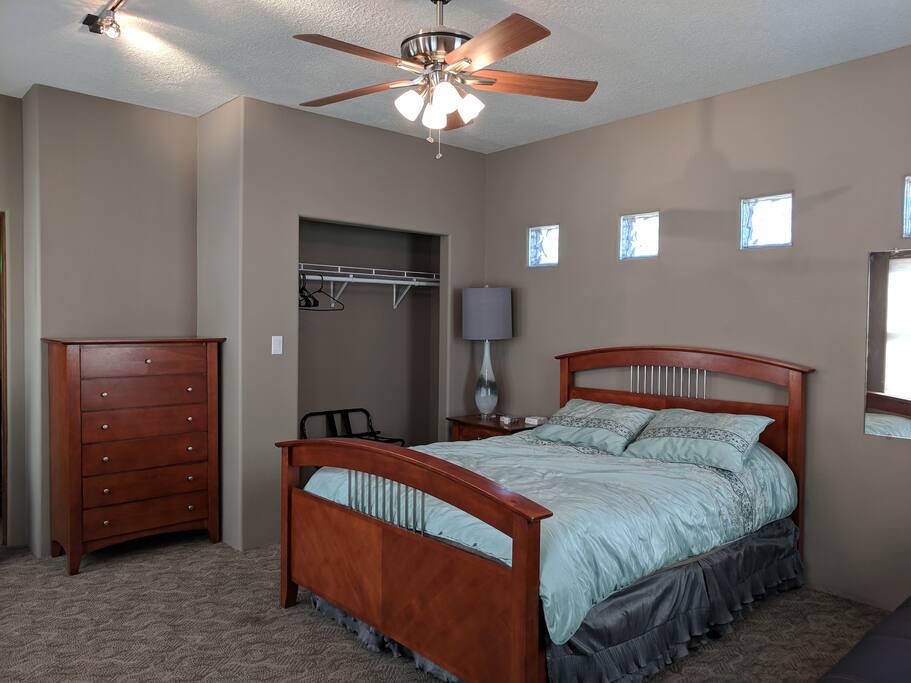 Newly remodeled room with closet, suitcase stand, dresser, and queen bed.