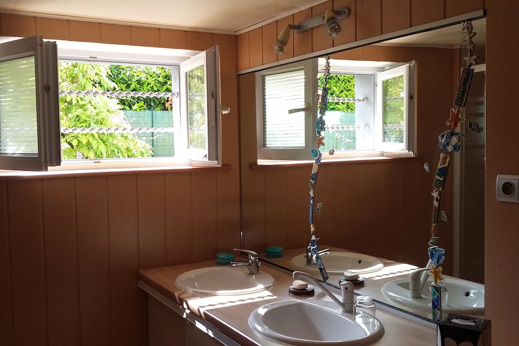cette pièce comporte un lavabo double vasque, une grande douche, un sèche serviette