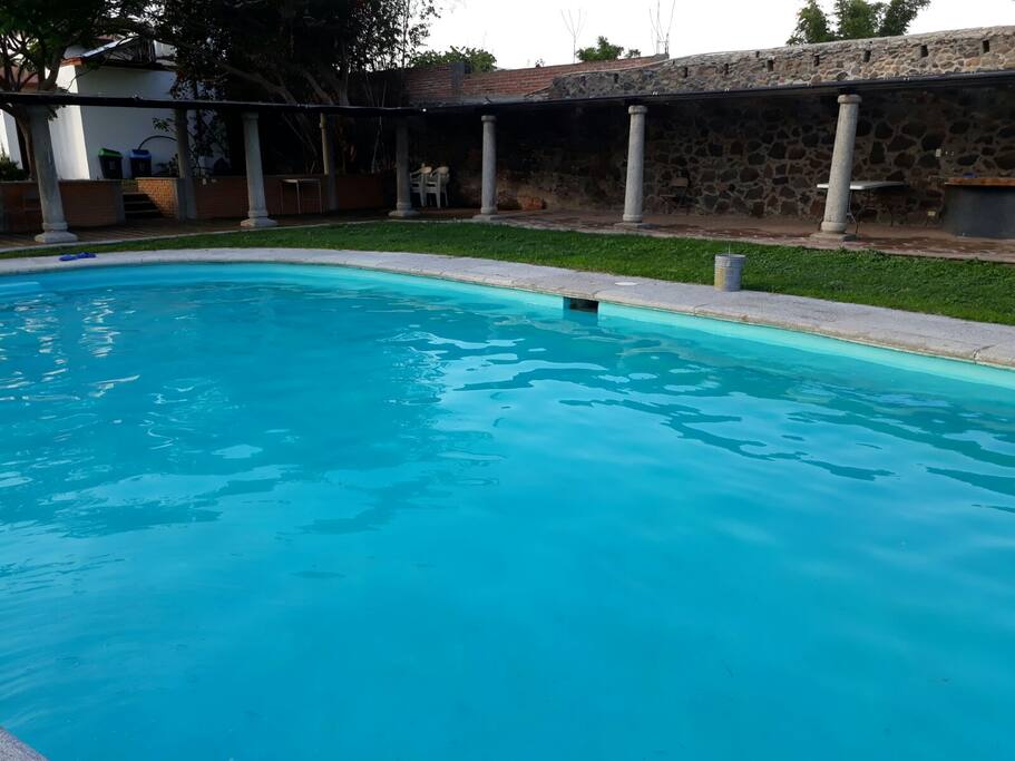 Alberca con agua templada por calentador solar, palapa y camastros