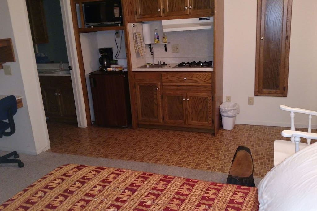 Kitchenette with small refrigerator, two burner cook top, microwave, toaster and coffee maker. Basic kitchen pots, pans and dishes.