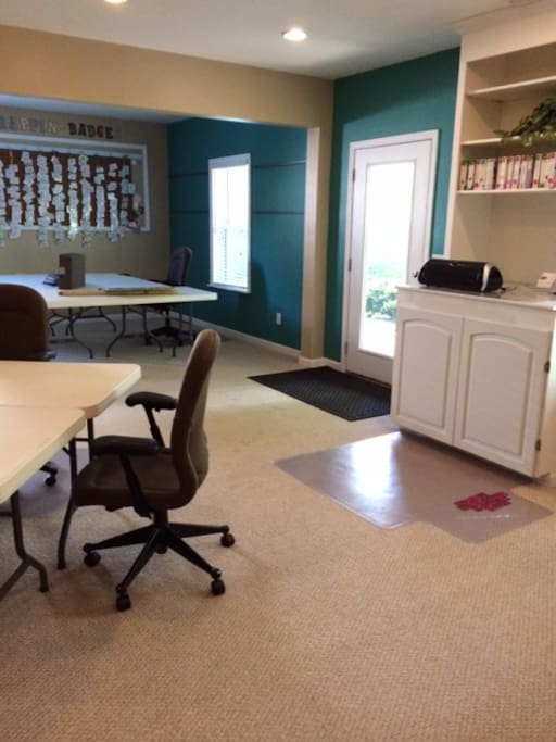The cropping room downstairs features 3 pods of tables, work stations containing scrapbooking tools and supplies.
